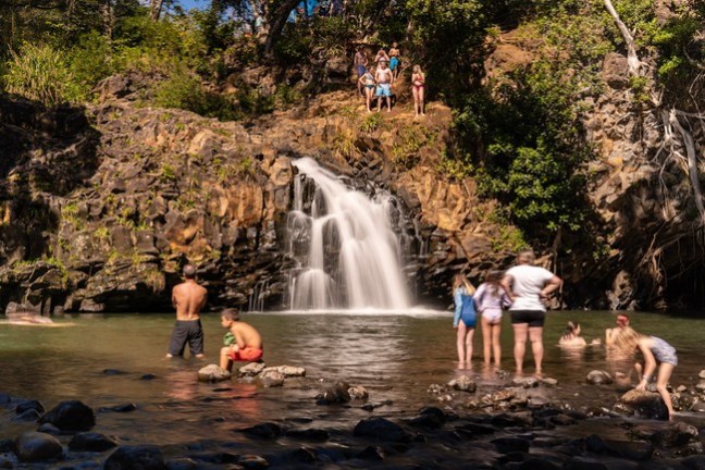 a group of people standing next to a waterfall